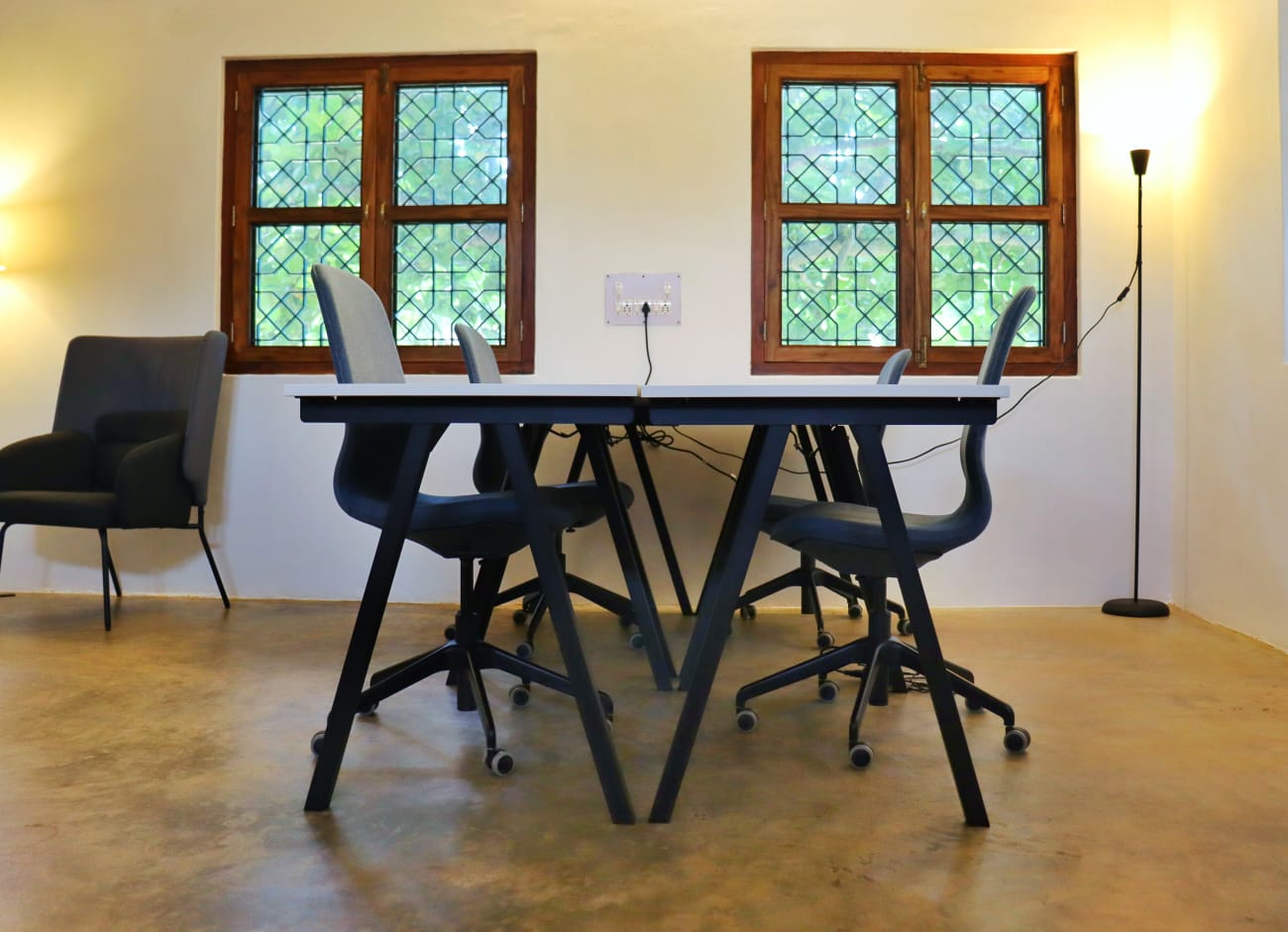 A four-person shared desk beneath stained-glass teak windows.